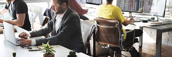 Lavoratori d'ufficio seduti alle scrivanie e che usano vari tipi di dispositivi ed endpoint