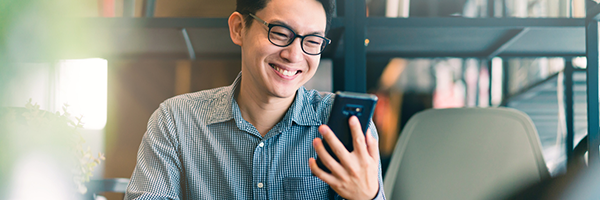 Uomo che sorride mentre tiene in mano e guarda un dispositivo Android